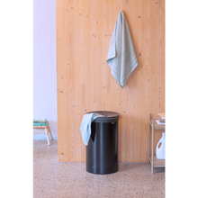 Load image into Gallery viewer, Lifestyle image of Brabantia Laundry Bin with Inner Removable Bag - 60 Liters, Matt Black.