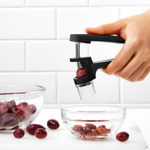 Load image into Gallery viewer, OXO Good Grips Olive &amp; Cherry Pitter - Black, in use.
